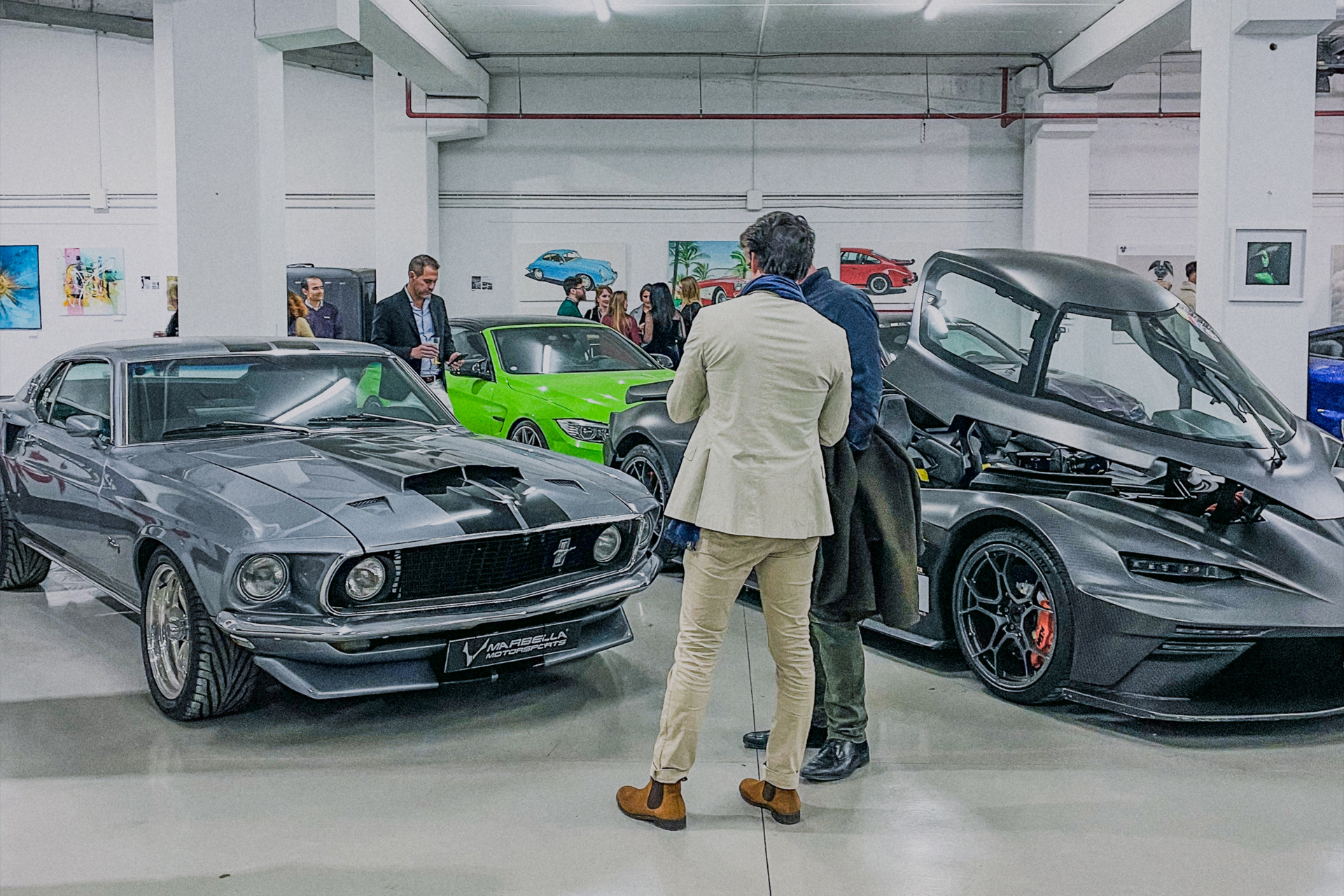 Residents viewing displayed cars at an indoor exhibit